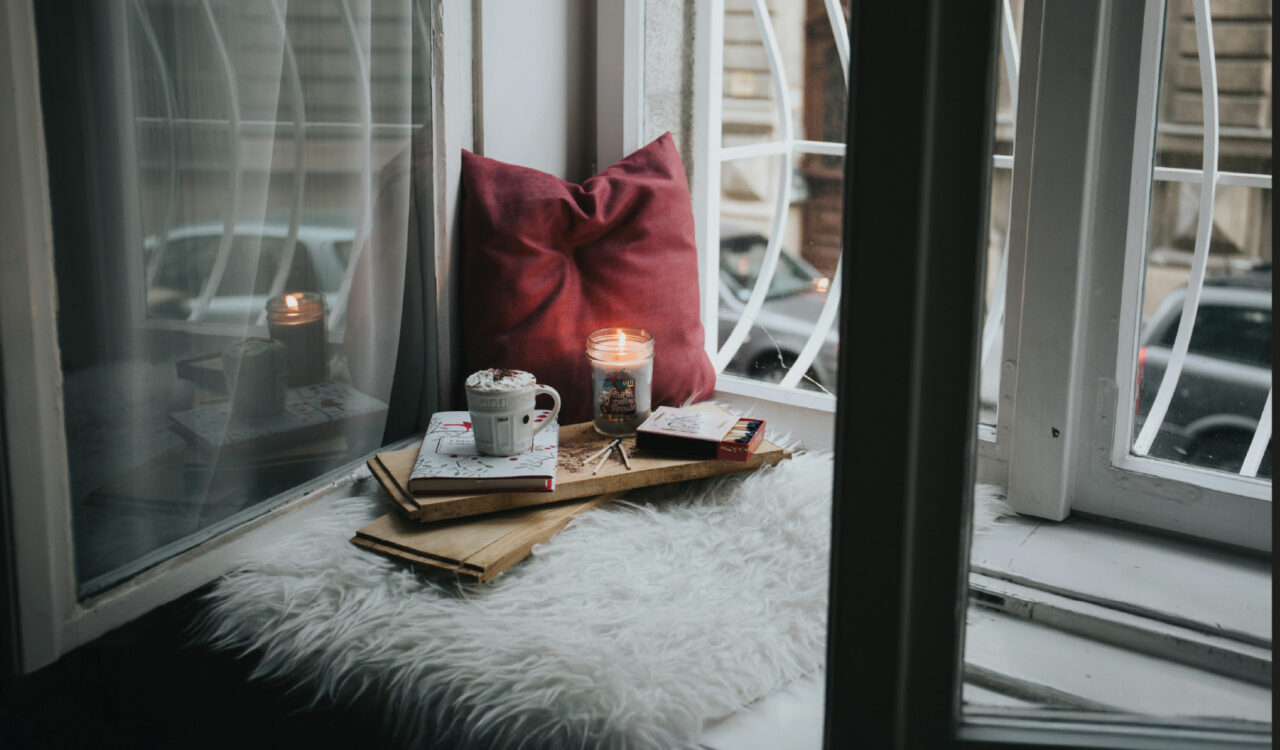 Eine gemütliche Ecke mit Kissen und Kerzen auf einer Fensterbank