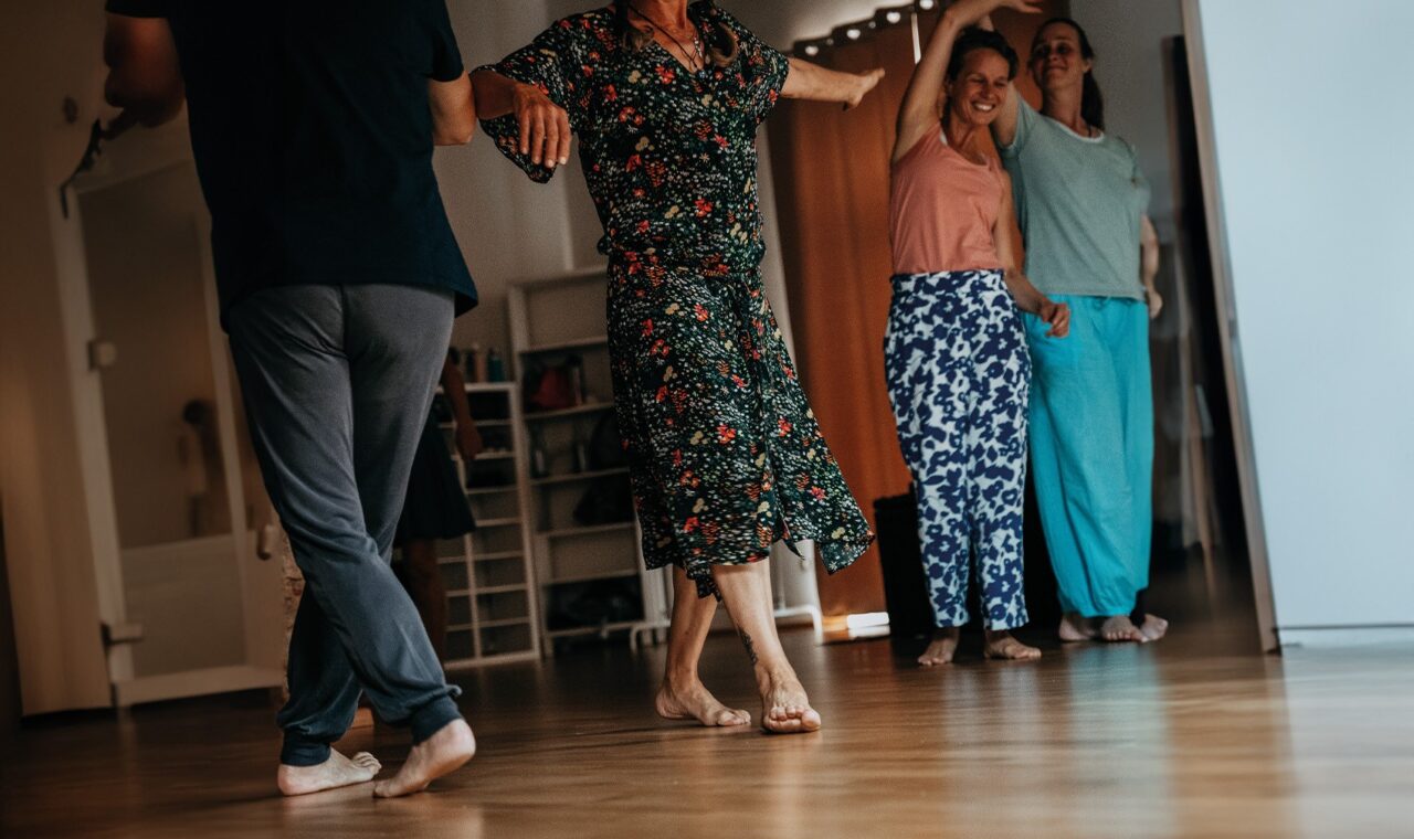 Personen in Freizeitkleidung tanzen barfuß in einer Wohnung
